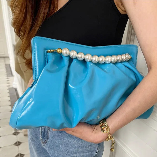 Bolsa clutch grande azul vibrante, em material sintético com efeito brilhante e drapeado. Detalhe frontal com alça de pérolas grandes douradas. Inclui alça dourada removível. Perfeita para eventos noturnos e ocasiões especiais.