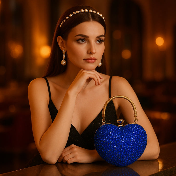 Mulher em balcão com sua linda Bolsa clutch festa azul em formato de coração, cravejada com cristais azuis vibrantes, alça metálica dourada estruturada e fecho superior com detalhe em pedra – loja Bolsa Clutch