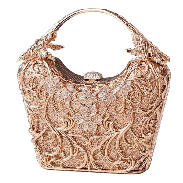 Bolsa feminina clutch festa dourada com acabamento metálico rendado, alça rígida escultural e aplicação de flores em strass, design exuberante e sofisticado – loja Bolsa Clutch