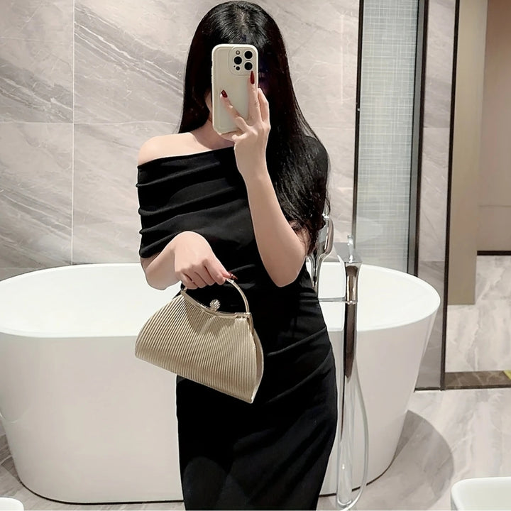 Mulher com a Clutch festa prata com brilho sutil dourado, formato trapezoidal e fecho com detalhe brilhante, peça glamourosa e elegante – loja Bolsa Clutch.