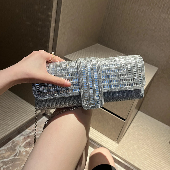 Mulher segurando a Bolsa clutch festa prata retangular com acabamento em strass tipo diamante, design estruturado com aba frontal e fecho magnético elegante – loja Bolsa Clutch