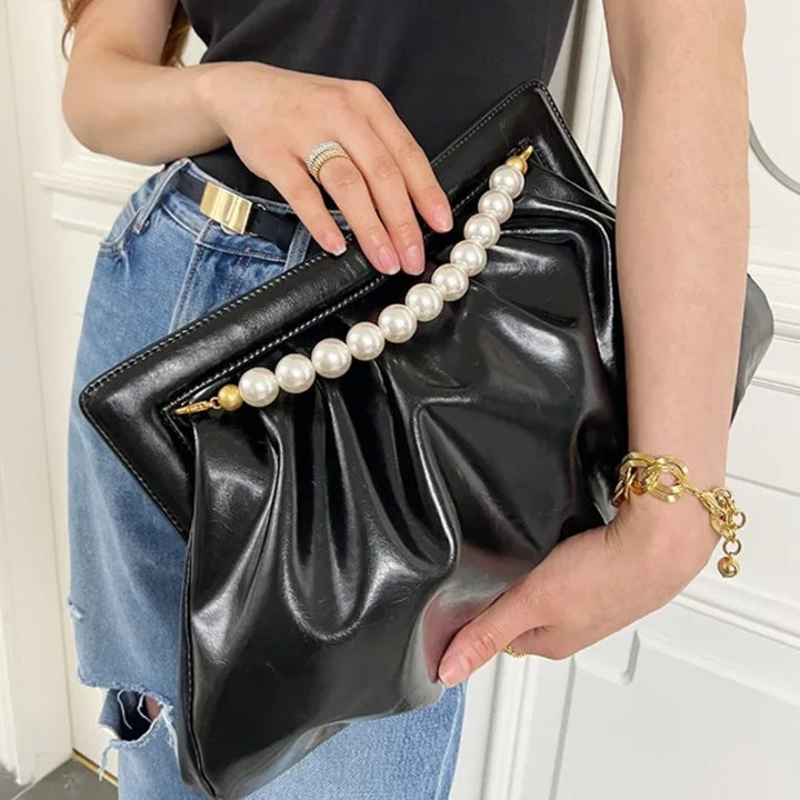 Bolsa feminina preta pérolas, linda e elegante, em material sintético com efeito drapeado. Possui alça superior fixa de pérolas brancas com terminais dourados. Tamanho médio, inclui bolso interno com zíper. Ideal para festas e eventos.