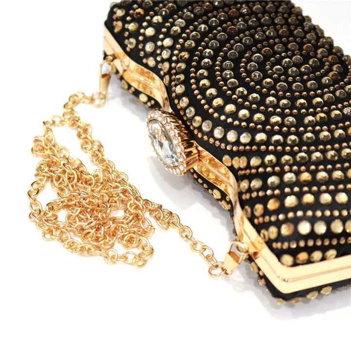 Clutch preta com pedrarias douradas em espiral, moldura metálica e fecho com cristal — ideal para looks glamourosos - loja Bolsa Clutch