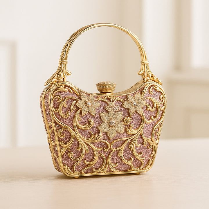 Bolsa Festa clutch na cor rosa com detalhes dourados com acabamento metálico rendado, alça rígida escultural e aplicação de flores em strass, design exuberante e sofisticado – loja Bolsa Clutch
