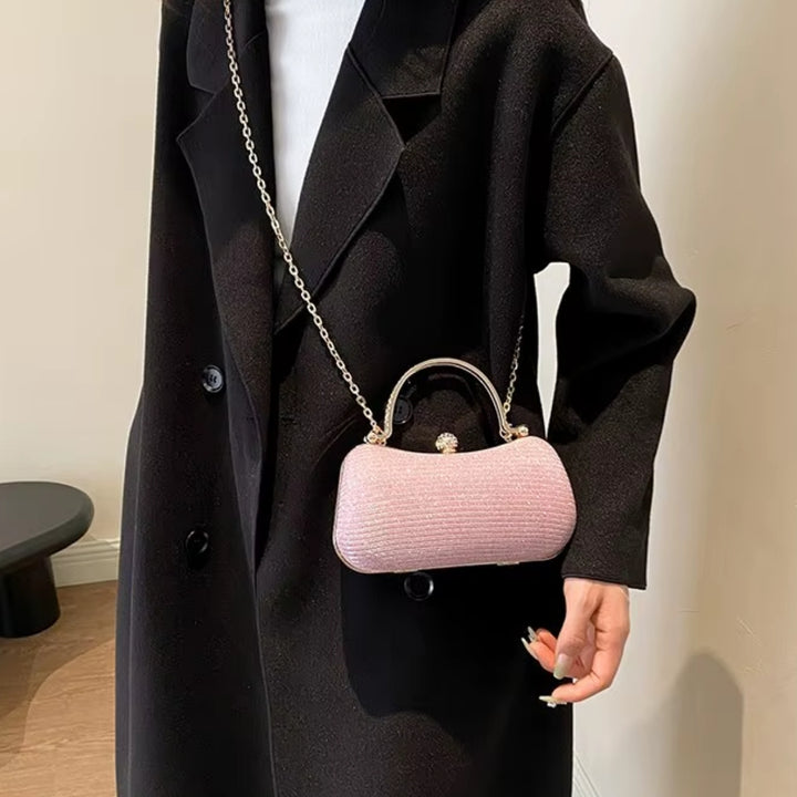 Bolsa de mão clutch festa rosa elegance com brilho, design retangular arredondado. Alça de mão superior dourada com strass, fecho de esfera cravejada e alça de corrente fina. Perfeita para eventos especiais e festas.