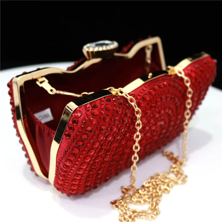 Interior e detalhes da corrente da Bolsa clutch vermelha com pedrarias e acabamento em cetim, fecho joia e moldura dourada com corrente de ombro — perfeita para festas de luxo - loja Bolsa Clutch