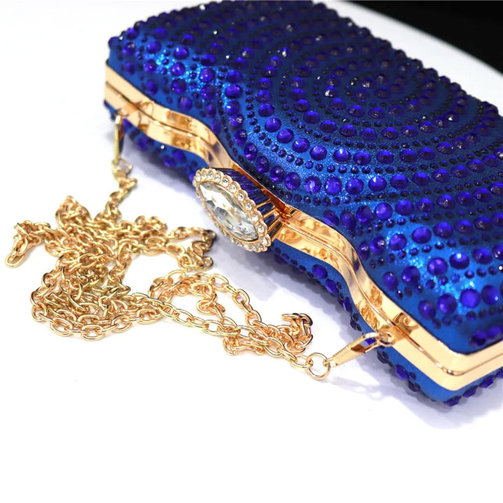 Bolsa clutch azul com aplicações brilhantes, fecho redondo cravejado e moldura metálica dourada — ideal para eventos sofisticados - loja Bolsa Clutch