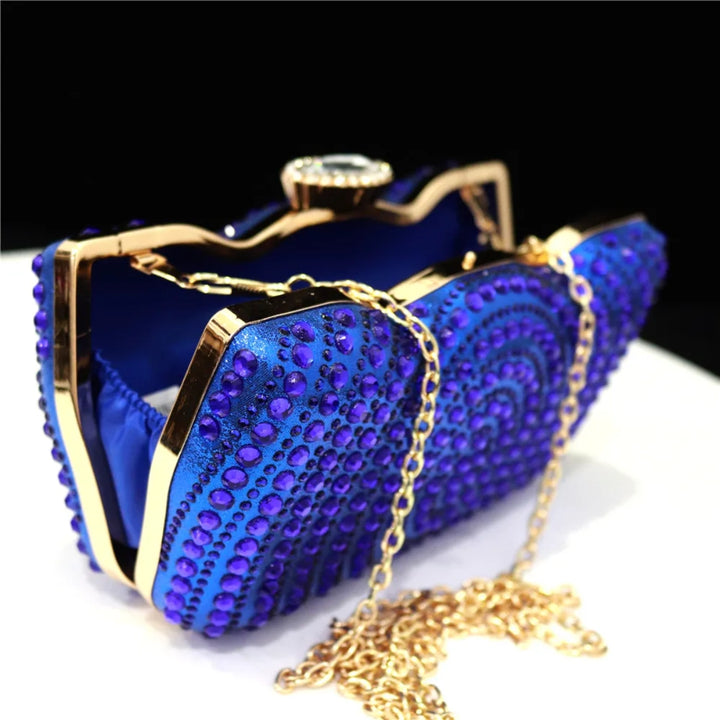 Bolsa de festa azul royal com textura brilhante, pedrarias em alto-relevo e corrente dourada destacando um visual luxuoso - loja Bolsa Clutch