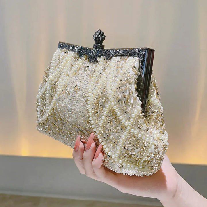 Mão segurando a Bolsa feminina clutch festa champagne com alça em corrente prata e alça de mão,  acabamento vintage bordado com pérolas e flores - loja Bolsa Clutch
