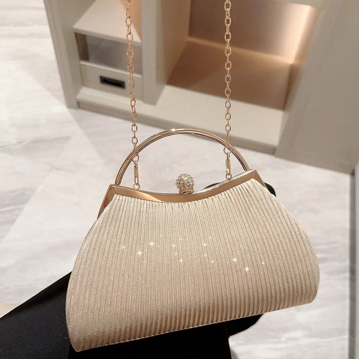 Linda Bolsa clutch festa prata com brilho dourado, tecido plissado elegante, alça metálica prateada estruturada, fecho com detalhe de joia e corrente fina removível – loja Bolsa Clutch