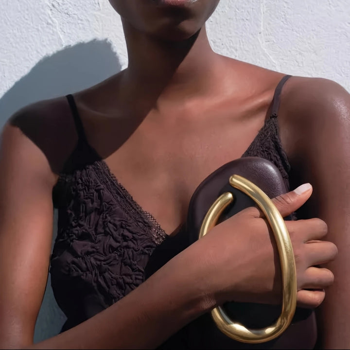 Mulher negra segurando a linda Bolsa de mão para festa clutch vermelha e dourada. lindo Design moderno com alça de mão dourada curva integrada e alça de corrente. Ideal para eventos.