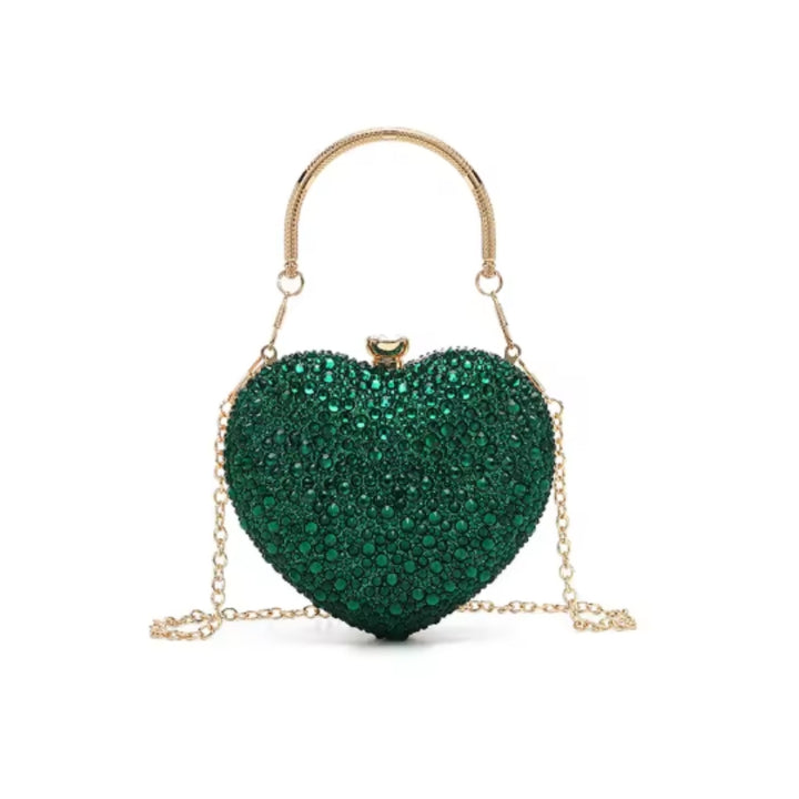 Bolsa clutch festa Verde em formato de coração, cravejada com cristais azuis vibrantes, alça metálica dourada estruturada e fecho superior com detalhe em pedra imagem com fundo branco – loja Bolsa Clutch